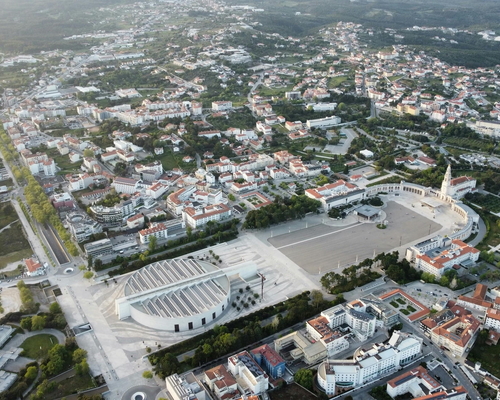 Weitwinkel-Luftaufnahme des Heiligtums von Fátima mit der Basilika, dem großen Pilgerplatz und umliegenden Gebäuden und Straßen im Stadtgebiet.